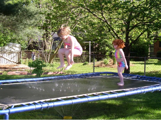 Lauren and Lydia jumping in the sprinkler